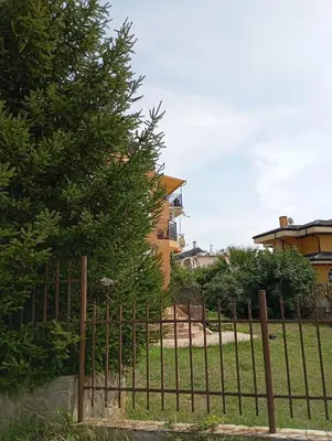 a fence in front of a house with a tree at Apartments Provence in Sozopol