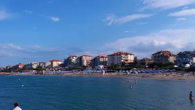 a beach with people in the water and buildings at Beach Apartment MELINA in Pomorie