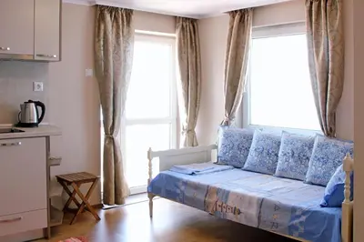 a small bedroom with a bed and two windows at Beach Apartment MELINA in Pomorie