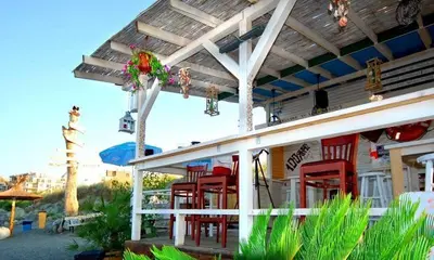 a building with red chairs and an umbrella at Beach Apartment MELINA in Pomorie