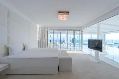 a white bedroom with a bed and a television at Grand Hotel Sveti Vlas - Fitness & SPA Hotel in Sveti Vlas