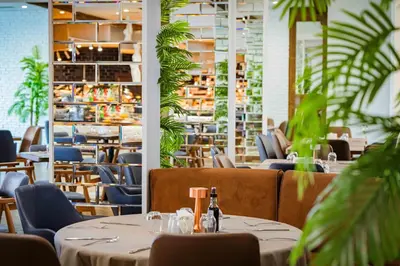 a restaurant with tables and chairs and plants at Grand Hotel Sveti Vlas - Fitness & SPA Hotel in Sveti Vlas