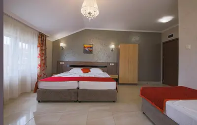 a bedroom with two beds and a chandelier at Guesthouse Phoenix in Obzor