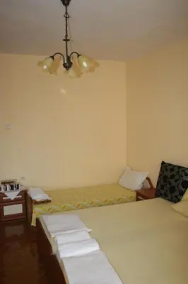 a bedroom with two beds and a table and a chandelier at Homestay Kostadinov in Pomorie