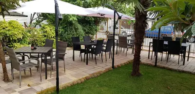 a patio with tables and chairs and an umbrella at Guest house Sineva in Primorsko