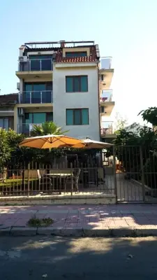 a building with a fence with tables and umbrellas at Guest house Sineva in Primorsko