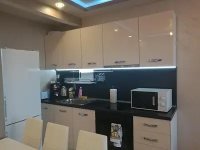 a kitchen with white cabinets and a sink and a microwave at Sunshine Apartment in Pomorie