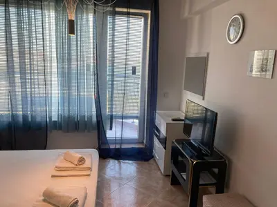 a bedroom with a bed and a television and a window at Apartments in Complex Panorama in Sozopol