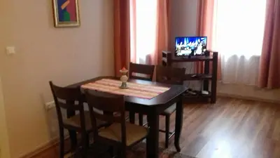 a dining room with a table and chairs and a television at Julia Garden in Burgas City