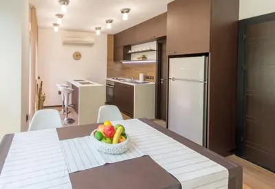 a kitchen and dining room with a table with a bowl of fruit at City Apartments La Casa in Varna City