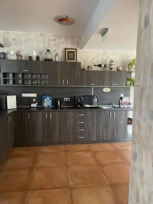 a large kitchen with wooden cabinets and a tile floor at Eco House Kitana in Tschenge