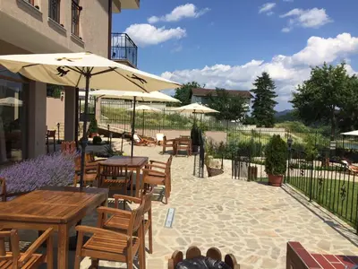 a patio with tables and chairs and an umbrella at Eco House Kitana in Tschenge