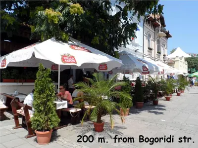 a restaurant with tables and umbrellas on a street at 4U Apartment in Burgas City