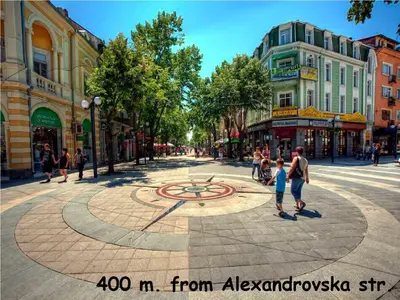 a group of people walking around a clock on a city street at 4U Apartment in Burgas City