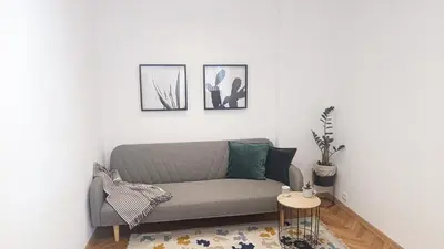 a living room with a gray couch and two pictures at Apartment Balabanov in Varna City