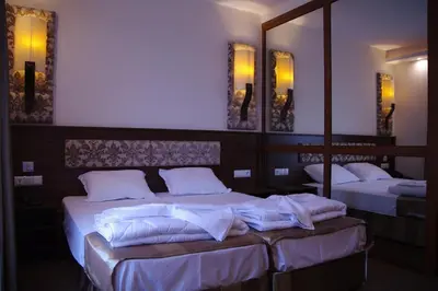 two beds in a room with mirrors and white sheets at Hotel Aristokrat in Obzor