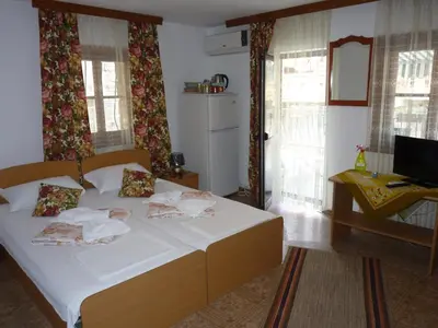 a bedroom with a bed and a desk and windows at Guest House Zhelevi in Sozopol