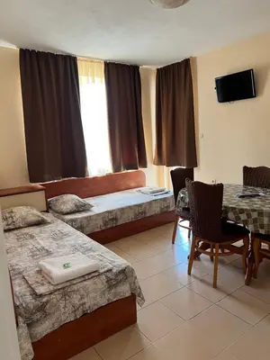 a room with two beds and a table and a table and chairs at Milchevi Guesthouse in Sozopol