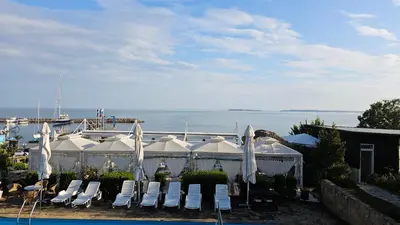 a group of white chairs and umbrellas by a pool at Complex Top Apartment in Sveti Vlas