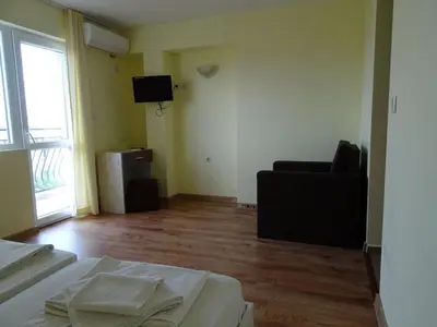 a room with a bed and a couch and a television at Kovachevi House in Primorsko