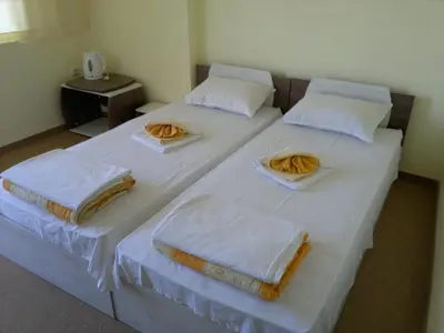two beds in a room with white sheets and towels at Kovachevi House in Primorsko