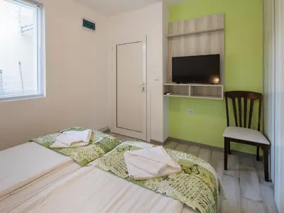 a bedroom with a bed with a chair and a television at Home Gramatikovi in Pomorie