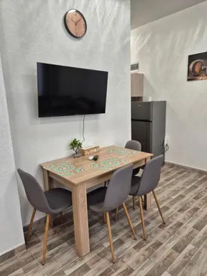 a dining room table with chairs and a clock on the wall at Студио Лазур Поморие in Pomorie