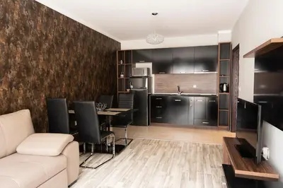 a living room with a couch and a kitchen at Green Paradise Deluxe Apartments in Primorsko