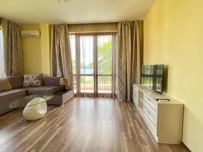 a living room with a couch and a tv at Green Paradise Deluxe Apartments in Primorsko