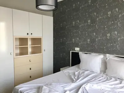 a bedroom with a white bed and a gray wall at Green Paradise Deluxe Apartments in Primorsko