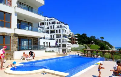 a group of people standing around a swimming pool next to a building at Бяла Виста Клиф - Byala Vista Cliff in Byala
