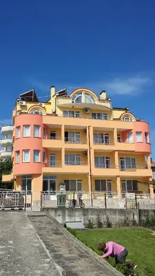 a woman standing in front of a large building at Zlatevi Guest House in Obzor