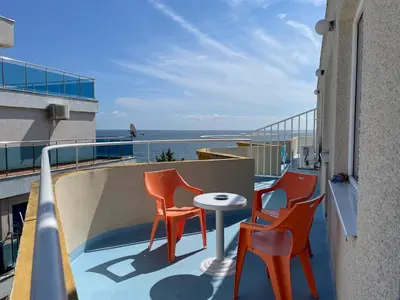two chairs and a table on a balcony with the ocean at Apartments Panorama Ravda in Ravda