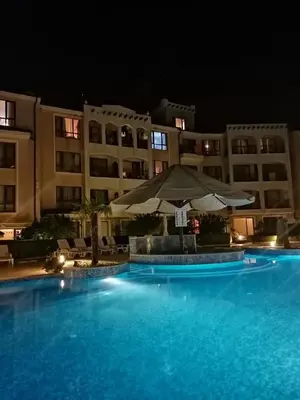 a large swimming pool with an umbrella next to a building at Paradise Bay D8 Apartment in Sozopol