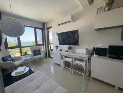a living room with a white couch and a table at Paradise Bay D8 Apartment in Sozopol
