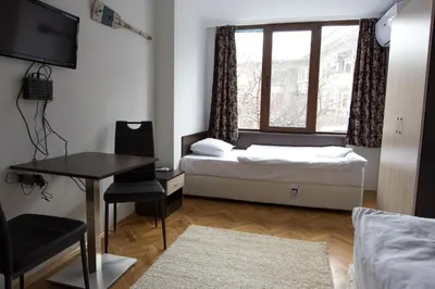a bedroom with a bed and a desk and a window at Guest Rooms Old Captain in Burgas City