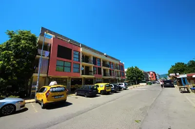 a street with cars parked in front of a building at Menada Crystal Park Apartments in Sunny Beach