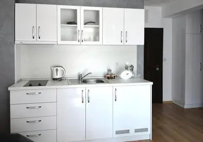 a white kitchen with a sink and white cabinets at Stela Apartments in Obzor