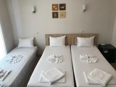 two beds in a small room with white sheets at Jane Guest House in Nesebar