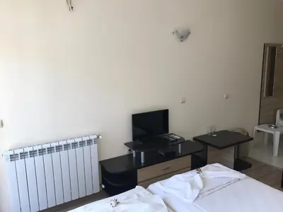a bedroom with a bed and a desk with a television at Jane Guest House in Nesebar