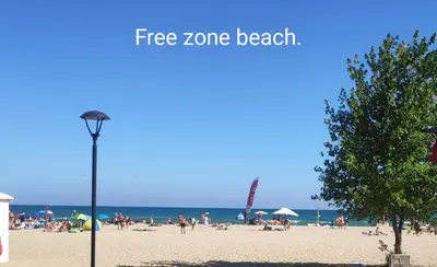 a beach with people on the sand and a street light at Hotel Shipka Beach in Sunny Beach