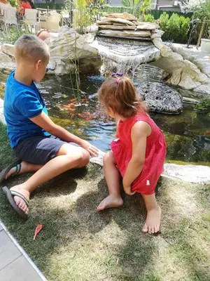 a boy and a girl sitting in front of a pond at Hotel Shipka Beach in Sunny Beach