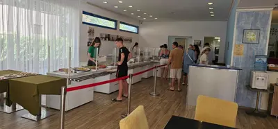 a group of people standing at a counter in a restaurant at Hotel Shipka Beach in Sunny Beach