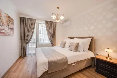 a bedroom with a large bed and a chandelier at Prestige Central Apartments in Varna City