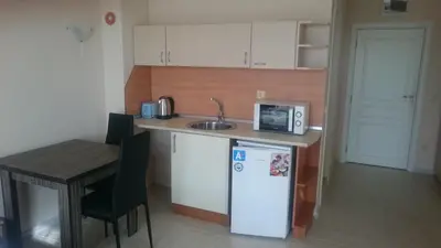 a small kitchen with a refrigerator and a table at Casa del Sol Apartments in Sunny Beach