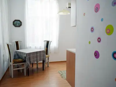a dining room with a table and chairs and a clock at Sea Garden in Burgas City