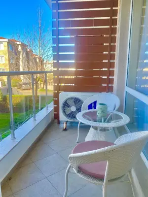 a balcony with a table and chairs and a fan at Apartments in Sunny Island Complex in Chernomorets