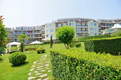 a garden with bushes and a building in the background at Apartments in Sunny Island Complex in Chernomorets