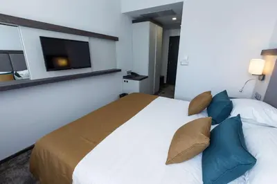a bedroom with a large bed with blue pillows at Best Western PLUS Premium Inn in Sunny Beach