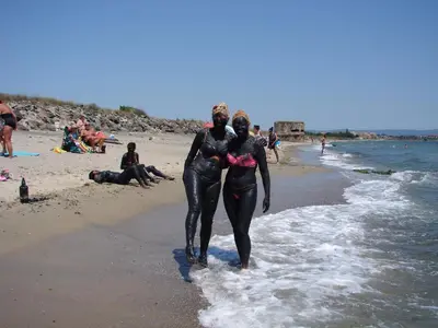 two people in wet suits walking on the beach at Apartament Aheloy in Aheloy